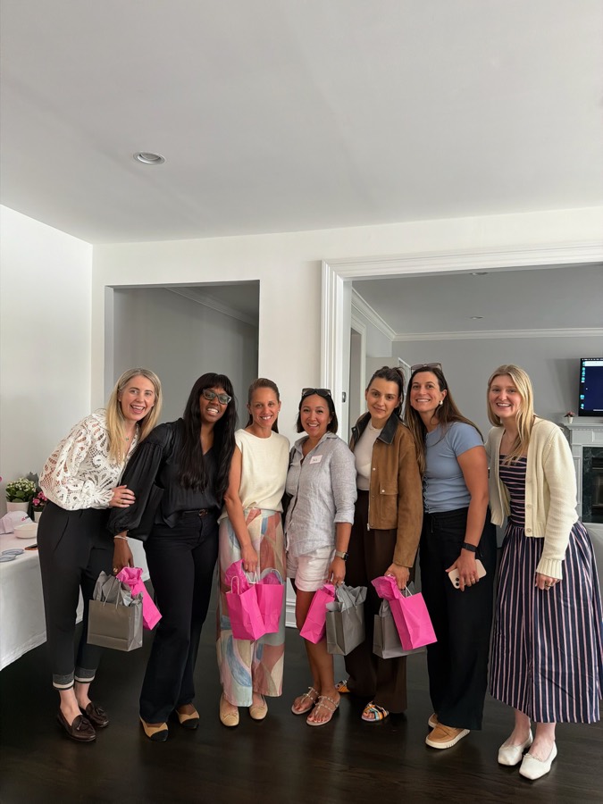 Moms holding pink ai.moms™ gift bags at an ai.moms™ event